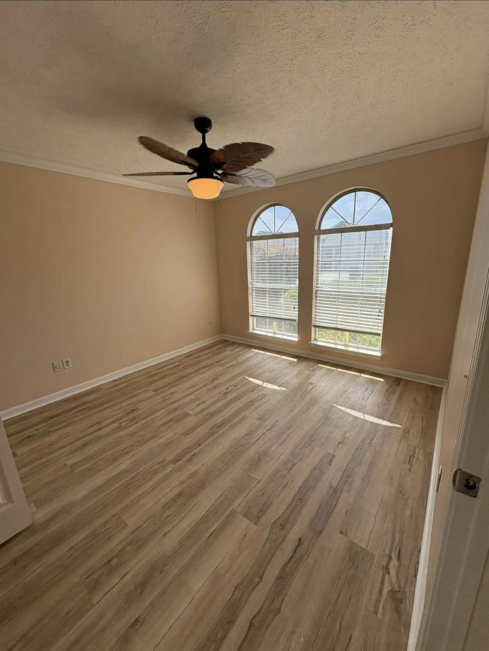 Bedroom with arched windows refreshed in warm neutral beige after painting