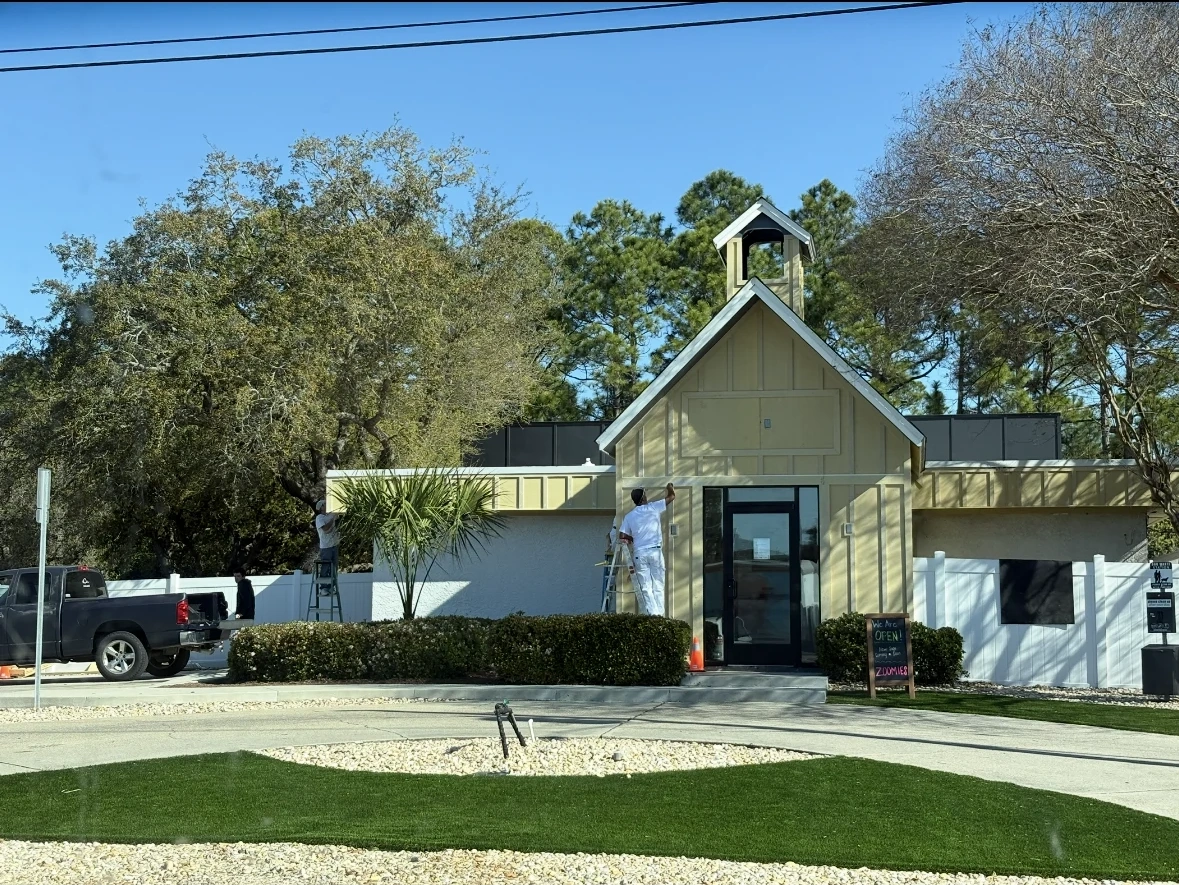Zoomies Pet Hotel and Daycare before repaint showing yellow Hardie board siding and prep work